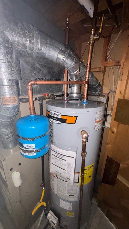 Completed installation of a 40-gallon STATE brand gas water heater in residential utility space with all necessary connections and safety components. Installed thermal expansion tank with proper copper piping connections, configured gas supply line using flexible yellow gas connector, and established hot and cold water distribution lines with brass shut-off valves. All plumbing connections were secured to manufacturer specifications, system was pressure tested for leaks, and unit was successfully commissioned and verified operational.