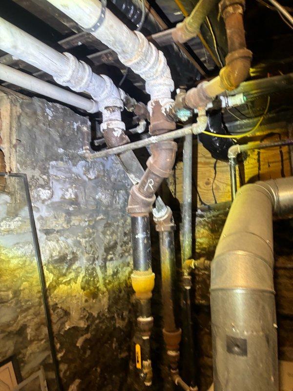 Conducted second opinion evaluation and provided estimate for low water pressure issue. Inspected galvanized water main located in closet area and measured static water pressure using calibrated gauge at exterior hose bib, which registered on WATTS pressure gauge. Documented existing copper supply piping configuration and assessed condition of aging galvanized water service line in basement/crawlspace area. Observed corrosion indicators on exposed piping, moisture staining on foundation walls, and signs of system deterioration. Photographed pressure testing equipment installation and existing plumbing infrastructure to support estimate for water service replacement recommendations.