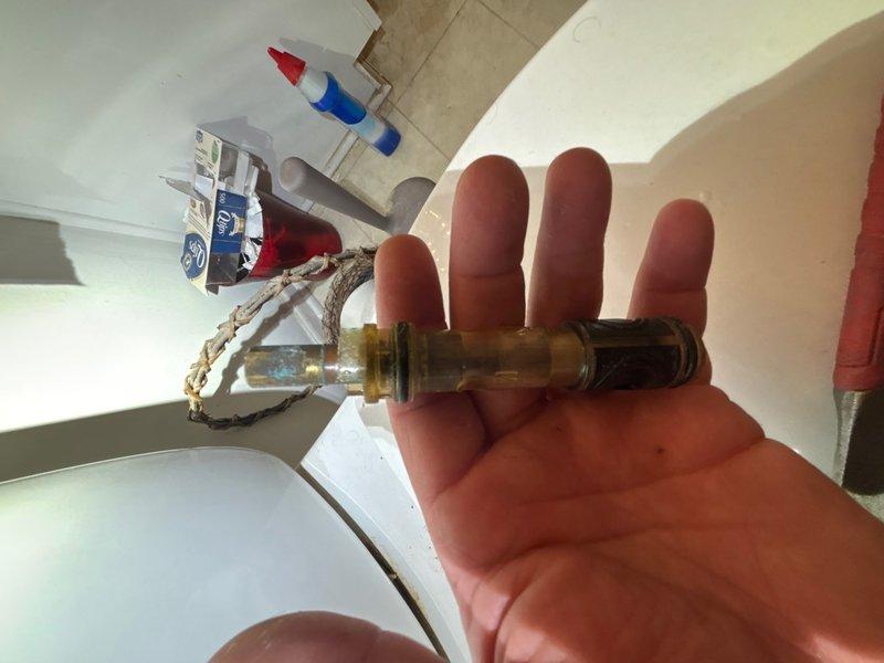 Responded to service call for dripping faucet underneath shower/tub fixture. Upon inspection, identified failed valve cartridge or stem assembly causing leak at base of faucet. Removed defective brass valve component and replaced with new fitting. Verified proper installation, tested water flow, and confirmed leak was eliminated. Unit restored to full working condition.