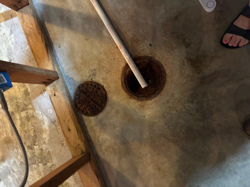 Performed second opinion inspection and video camera evaluation of drainage piping system. Documented floor drain conditions showing corrosion and age-related deterioration at drain openings, as well as inspected sump pump assembly with connecting PVC discharge lines in crawl space area. Identified rust staining and mineral deposits on pump components indicating potential maintenance concerns.