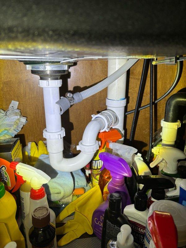 Performed routine plumbing maintenance inspection of water heating system and under-sink plumbing. Inspected Performax Gel water heater installation in utility closet, verifying proper copper piping connections, expansion tank mounting, and safety label compliance. Examined under-sink cabinet plumbing, confirming PVC trap assembly and drain connections were functioning properly with no visible leaks or drainage issues.