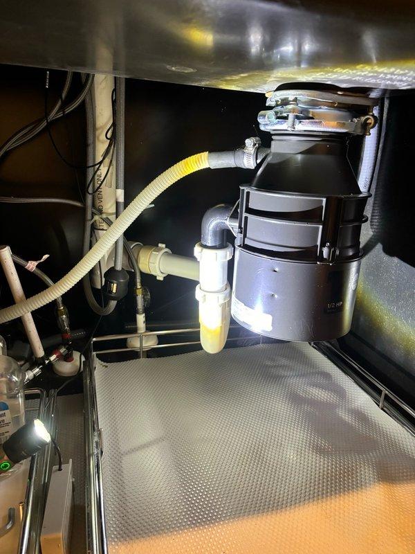 Responded to service call for garbage disposal issue in kitchen. Upon arrival, inspected InSinkErator 1/2 HP disposal unit installed beneath sink. Verified proper mounting of disposal to sink drain flange with secure bolt connections and rubber gasket seal. Examined all plumbing connections including P-trap configuration, dishwasher drain line, and discharge piping. Confirmed disposal unit operational status and proper drainage function. All components found secure with no visible leaks at mounting points or drain connections.