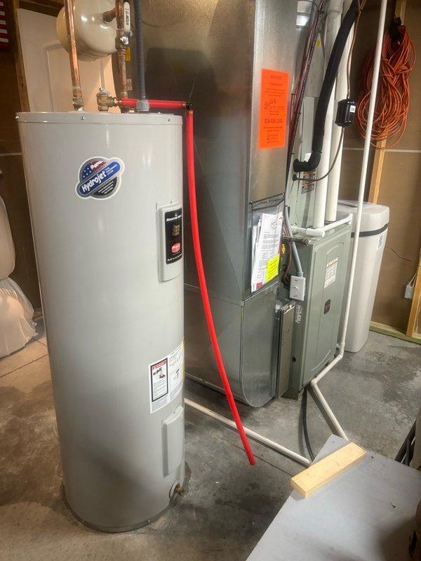 Responded to after-hours service call for leaking valve on top of tanked water heater in basement. Upon inspection, identified active leak at inlet connection requiring immediate attention to prevent water damage and restore proper system operation. Assessed water heater configuration including supply lines, shut-off valves, and associated plumbing connections. Documented equipment condition and leak source with photographic evidence showing InSinkErator water heater unit with copper supply piping and shut-off valves. Provided repair recommendations to address the valve leak and restore system integrity.