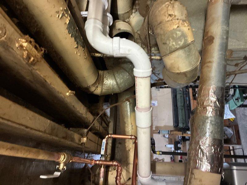 Completed installation of Rinnai RX160 condensing tankless water heater with 96% efficiency and 9.0 GPM capacity in basement utility area. Removed and properly disposed of existing conventional water heater, capping old gas lines and venting as required. Installed approximately 15 feet of 2-inch PVC piping for combustion air intake and exhaust venting with appropriate termination. Ran hot and cold water supply lines to unit using copper piping. Installed gas supply line using black iron pipe with required tee fittings, 90-degree elbows, sediment trap, and emergency shut-off valve for code compliance. Routed condensate drain line to existing floor drain with proper air gap and venting below unit to prevent trap siphoning. Verified dedicated 110-volt electrical outlet was present at installation location. Tested unit operation by running multiple fixtures throughout the house to confirm proper flow rate, temperature control, and system functionality. All work completed to manufacturer sp