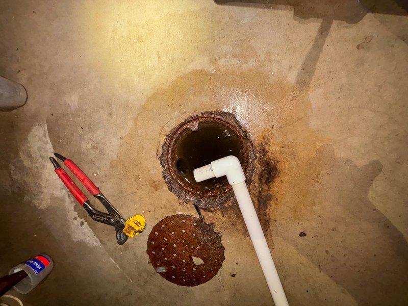 Responded to a clogged drain issue in the basement utility area. Upon arrival, accessed the floor drain and sump pit, which showed significant rust staining and drainage obstruction. Removed the perforated metal strainer cover, cleared the blockage from the drain opening and PVC discharge line, and restored proper water flow. Tested the system to ensure complete drainage functionality before completing the service call.