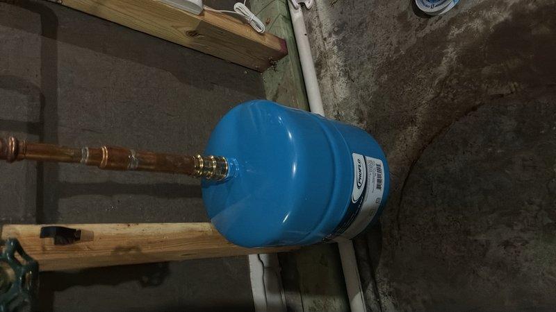Responded to callback for water heater leaking from bottom in basement. Upon inspection, confirmed active leak requiring bucket placement beneath unit. Assessed pressure tank connections and copper piping with brass fittings for potential sources of water accumulation. Documented existing conditions including PVC drainage system, expansion tank installation, and structural support configuration to determine appropriate repair solution.