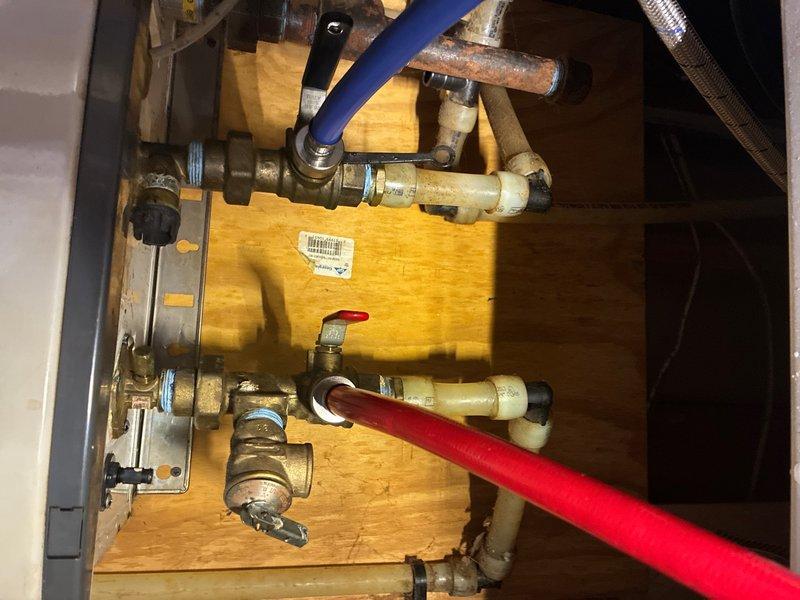 Performed routine maintenance on tankless water heater system located on ground floor, completing scheduled flush procedure and preventive plumbing maintenance inspection. Serviced plumbing assembly including brass valves, compression fittings, and flexible supply lines connected to the water heating unit mounted on wooden platform. All connections, ball valves, and distribution piping inspected and confirmed secure with proper operation of control system and circulation components.