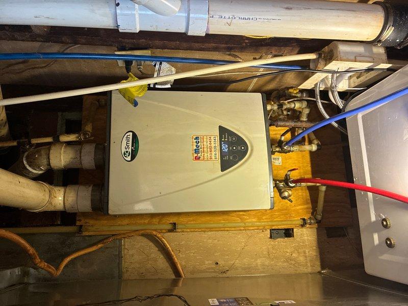 Performed routine maintenance on tankless water heater system located on ground floor, completing scheduled flush procedure and preventive plumbing maintenance inspection. Serviced plumbing assembly including brass valves, compression fittings, and flexible supply lines connected to the water heating unit mounted on wooden platform. All connections, ball valves, and distribution piping inspected and confirmed secure with proper operation of control system and circulation components.