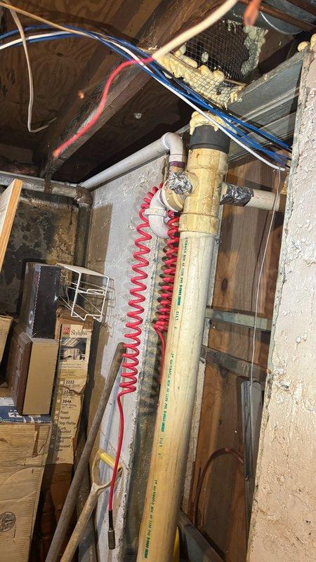 Conducted comprehensive on-site assessment of basement sewer and drain line system to provide estimate for necessary repairs and replacements. Inspection revealed severely deteriorated concrete flooring around main sewer line penetrations, with extensive fragmentation and soil exposure creating potential structural and sanitary concerns. Evaluated condition of existing PVC drain lines, including vertical stack and angled lateral connections, noting age-related discoloration and wear patterns. Documented compromised floor conditions requiring concrete removal and replacement to properly access and service underground sewer lines. Assessed overhead plumbing infrastructure, water supply lines, and electrical routing to determine scope of work and potential conflicts during excavation and installation phases.
