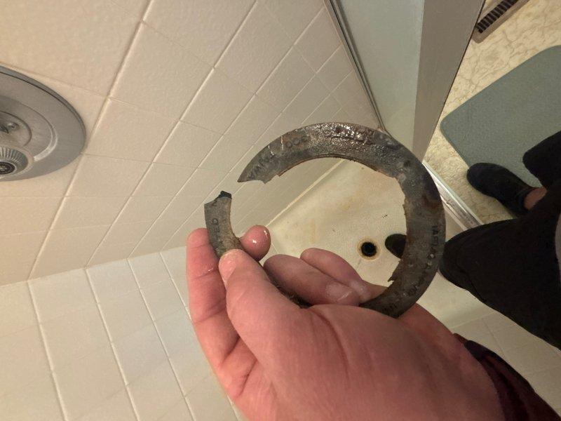 Responded to reported water leak from shower into garage. Upon inspection, identified failed shower drain gasket as the source of the leak. The drain assembly exhibited significant deterioration, with visible corrosion, rust buildup, and mineral deposits around the drain fixture. Removed the corroded drain ring, which showed extensive oxidation and moisture damage throughout. Replaced the failed gasket and drain components to restore proper seal and prevent further water intrusion into the garage below.