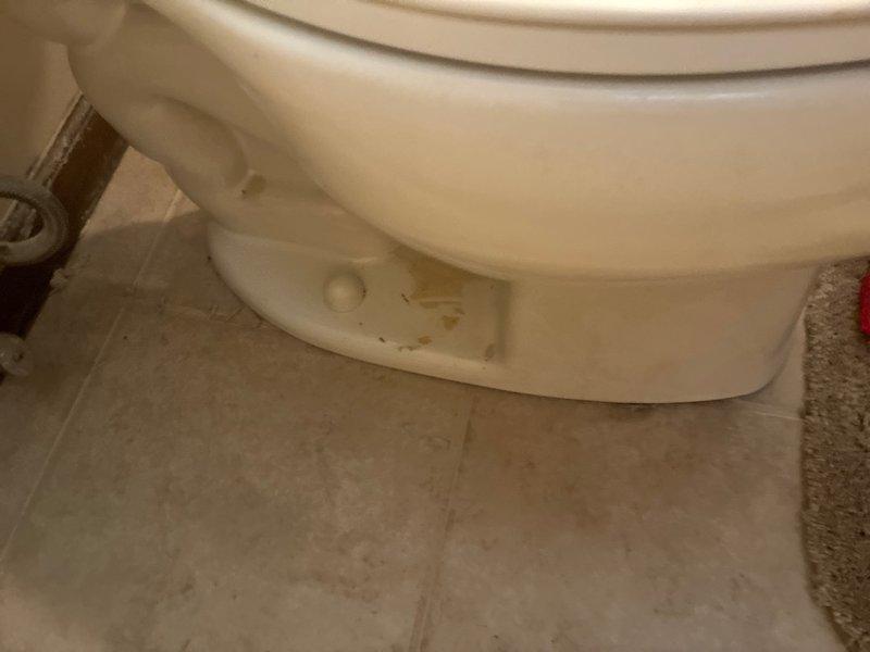Responded to water leak complaint with visible water damage on kitchen ceiling directly below upstairs bathroom. Upon inspection, identified toilet as source of leak with evidence of water staining and discoloration at base connection point where fixture meets floor. Documented conditions showing compromised seal at toilet base with visible moisture intrusion through ceiling below. Recommended immediate repair or replacement of wax ring seal and proper resetting of toilet to prevent continued water damage to ceiling and underlying structure.