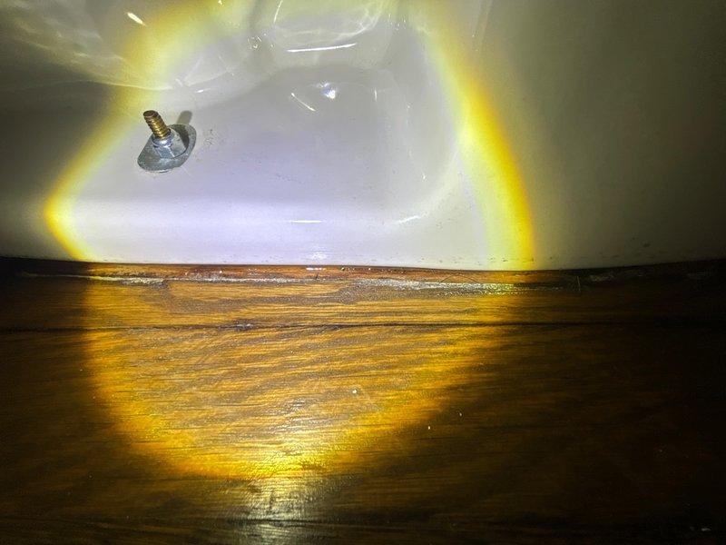 Responded to reported toilet leak in bathroom. Upon inspection, discovered active water seepage at the base of the toilet where it meets the wooden floor, with visible moisture damage to surrounding wood planks. Removed toilet from floor flange to assess source of leak. Found compromised wax ring seal allowing water to escape during flushing. Removed failed wax ring, cleaned toilet flange and horn, and installed new wax ring seal. Reinstalled toilet, ensuring proper alignment with flange bolts and secure mounting to floor. Tested flush operation multiple times to verify leak was eliminated and seal is functioning properly.
