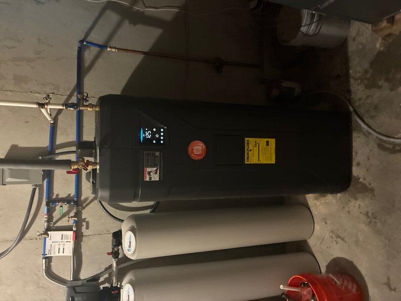 Completed installation of new tanked water heater system in residential utility space. Installed main water heater unit with proper electrical connections via junction box, including appropriate wire terminations and conduit fittings. Configured integrated plumbing manifold system using PEX piping with shutoff valves, connected expansion tanks, and installed pressure relief valve per code requirements. Verified all electrical connections, tested system operation, and confirmed proper temperature display functionality upon startup.