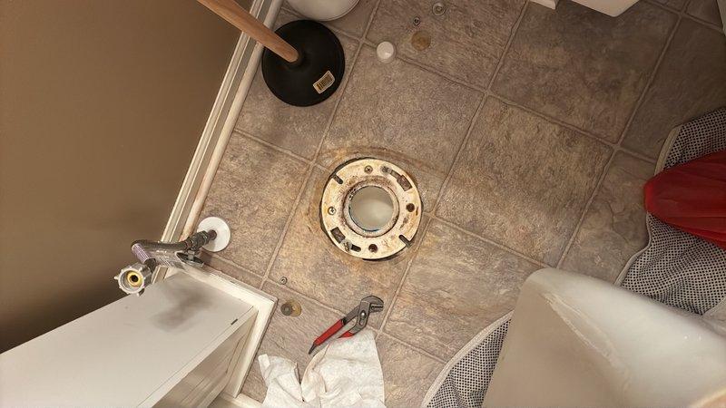 Responded to reported leak at toilet base in second floor guest room. Upon inspection, identified water seepage originating from deteriorated wax ring seal between toilet fixture and closet flange. Shut off water supply at angle stop valve and drained toilet tank and bowl completely. Disconnected water supply line and removed closet bolts securing toilet to flange. Lifted and removed toilet fixture to access mounting area.

Removed old wax ring and cleaned both toilet horn and closet flange surfaces of residual wax and debris. Inspected closet flange for damage and verified proper condition and secure mounting to subfloor. Installed new wax ring with integrated polyethylene flange onto toilet horn. Carefully repositioned toilet over closet flange, ensuring proper alignment with mounting bolts. Compressed wax seal by applying even downward pressure while checking level of fixture. Installed new brass closet bolts with washers and nuts, tightening in alternating pattern to manufacturer s