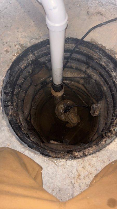 Responded to service call for non-operational sump pump system that had been inoperable for approximately two years. Upon arrival, performed comprehensive assessment of existing sump pump installation in basement location. Inspected sump basin, pump unit, electrical connections, and discharge piping system. Found pump had failed and required replacement. Removed old pump assembly from basin and cleared debris from pit bottom. Installed new sump pump unit with appropriate float switch mechanism. Verified proper electrical connections via existing wiring and conduit system mounted to basement wall. Connected discharge piping to white PVC pipe assembly. Tested pump operation through multiple cycles to ensure proper activation, water removal, and automatic shut-off functionality. Confirmed basin draining correctly and all connections secure with no leaks detected. System restored to full working order.