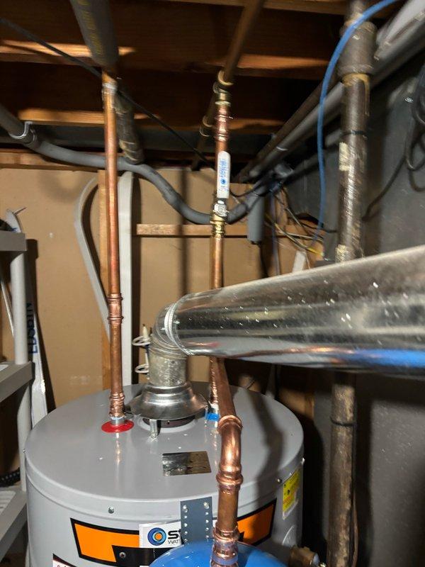 Completed installation of a 50-gallon gas water heater in the mechanical room with all required components and safety devices. Installed a thermal expansion tank to protect the plumbing system from excessive pressure buildup caused by thermal expansion during the heating cycle. Connected all copper supply lines with proper brass fittings, ensuring secure joints and leak-free operation. Mounted the expansion tank in accordance with manufacturer specifications and local plumbing codes. Installed a pressure relief valve with discharge piping and verified proper pressure gauge functionality, confirming system pressure remains within the safe operating range indicated by the color-coded dial. Secured all piping to floor joists using appropriate hangers and strapping to prevent stress on connections and minimize vibration. Tested the complete system for proper operation, verifying gas connections, water flow, and temperature controls are functioning correctly.