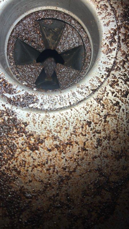 Responded to kitchen sink clog affecting the garbage disposal side of a double-basin sink. Upon inspection, found significant buildup of organic matter, grease, and debris accumulated in the disposal unit and drain line, causing complete backup when water was introduced. Disassembled and cleaned the garbage disposal impeller assembly, which showed heavy corrosion and mineral deposits on interior walls. Removed accumulated food waste and grease from disposal chamber and drain components. Cleared blockage from disposal discharge line and verified proper drainage. Cleaned sink basin and drain fitting areas of residue buildup. Tested disposal operation and water flow to confirm complete restoration of drainage function.