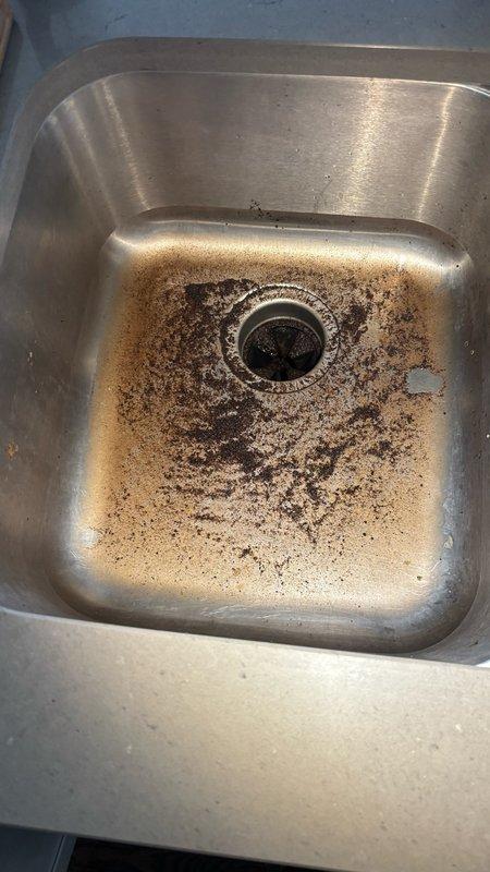 Responded to kitchen sink clog affecting the garbage disposal side of a double-basin sink. Upon inspection, found significant buildup of organic matter, grease, and debris accumulated in the disposal unit and drain line, causing complete backup when water was introduced. Disassembled and cleaned the garbage disposal impeller assembly, which showed heavy corrosion and mineral deposits on interior walls. Removed accumulated food waste and grease from disposal chamber and drain components. Cleared blockage from disposal discharge line and verified proper drainage. Cleaned sink basin and drain fitting areas of residue buildup. Tested disposal operation and water flow to confirm complete restoration of drainage function.