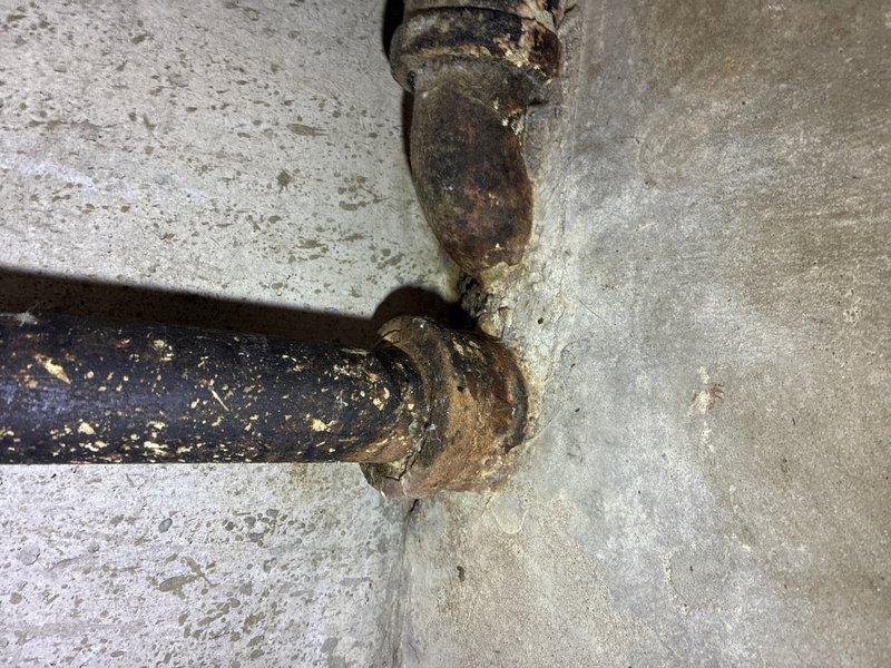 Responded to leak investigation call for basement plumbing issue. Upon arrival, conducted thorough inspection of cast iron drain system. Located severely corroded cast iron drain pipes at floor and wall junction showing extensive surface deterioration, flaking coating, and heavy rust accumulation. Documented pipe condition with photographs revealing compromised pipe integrity at base flange connection and vertical-to-horizontal pipe junction. The advanced corrosion and pitting observed on the cast iron drain lines indicated prolonged moisture exposure and age-related degradation, consistent with reported leak concerns. Advised customer of findings and recommended replacement of affected cast iron drain sections to prevent future leakage and potential water damage.