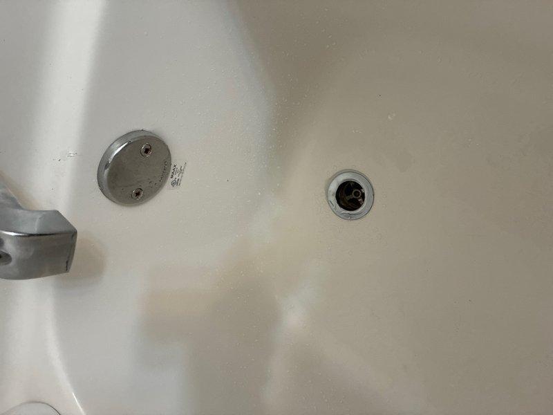 Responded to water leak concerns in kitchen and basement areas of 15-year-old residential property. Upon inspection, identified bathtub drain assembly requiring attention, with visible water staining and mineral deposits on tub surface indicating potential overflow or drainage issues. Removed and inspected drain cover and overflow plate, checking for proper sealing and secure mounting. Cleaned drain assembly, resealed fixtures, and verified proper water flow to prevent future leakage into lower levels.