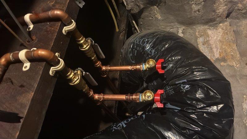 Installed two shut off valves and two boiler drains on the copper supply lines serving the washing machine. This installation enables proper drainage of the water lines during winter months, preventing freeze damage to the plumbing system. All components were mounted securely to a backing board with appropriate support brackets, and brass fittings with red-handled ball valves were utilized for reliable operation and easy identification.