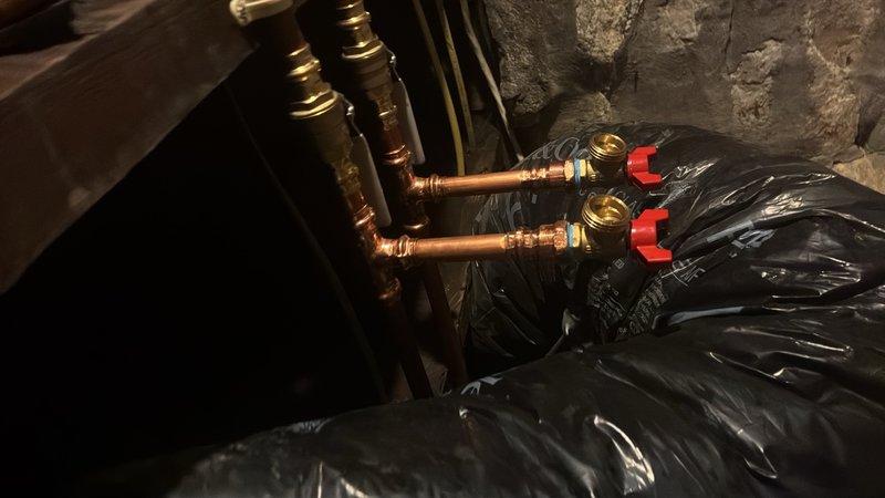 Installed two shut off valves and two boiler drains on the copper supply lines serving the washing machine. This installation enables proper drainage of the water lines during winter months, preventing freeze damage to the plumbing system. All components were mounted securely to a backing board with appropriate support brackets, and brass fittings with red-handled ball valves were utilized for reliable operation and easy identification.