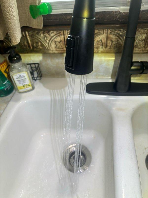 Completed installation of customer-supplied kitchen faucet, replacing existing fixture. Removed old faucet assembly and disconnected supply lines from shutoff valves beneath sink. Installed new matte black pull-down faucet with spray functionality, connecting braided stainless steel supply hoses to existing brass fittings and shutoff valves. Secured faucet mounting hardware to sink deck and tightened all connections. Tested water flow and spray function on both hot and cold supply lines, verified proper operation of pull-down spray head, and inspected all connections for leaks. System operating correctly with no leaks detected.