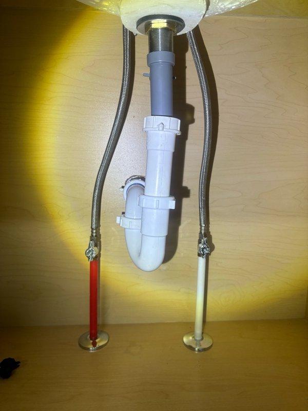 Replaced zinc faucet assembly in master bathroom with new chrome two-handle faucet featuring traditional cross-style handles and polished finish. Installed new braided stainless steel flexible water supply lines connected to hot and cold shut-off valves. Verified proper P-trap configuration and drain assembly connections, ensuring all fittings are secure and leak-free. Tested water flow and handle operation to confirm proper functionality of the new fixture.