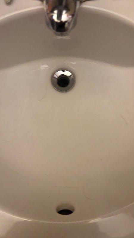 Responded to service call for clogged main floor bathroom sink with backup issue. Upon arrival, contacted customer 30 minutes prior as requested and arrived within scheduled window. Inspected white porcelain sink with chrome drain assembly and determined blockage in drain line causing water backup. Cleared obstruction using appropriate drain clearing methods, restoring proper drainage and flow. Tested sink operation to confirm issue resolved and drain functioning normally.