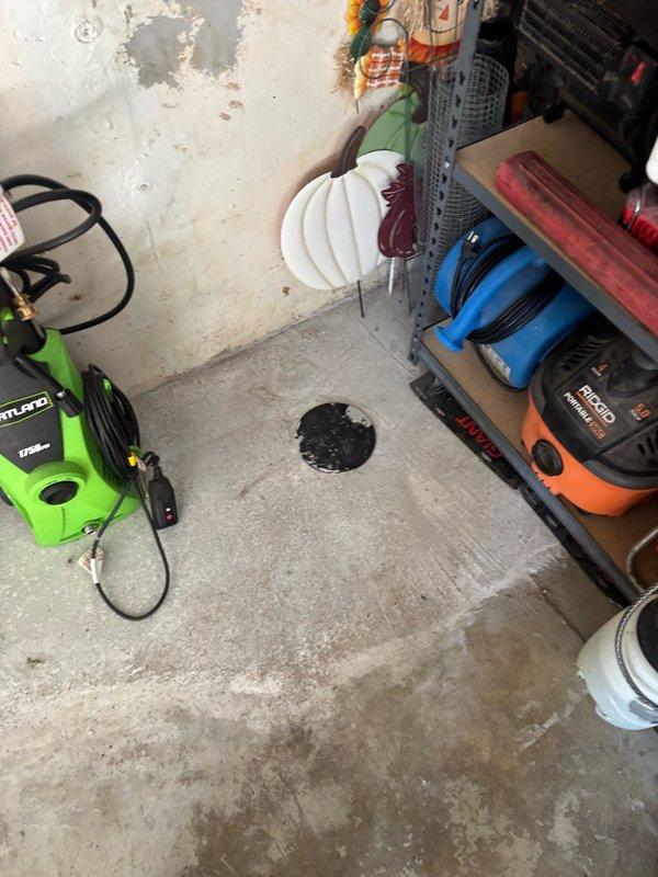 Installed new backwater valve on main sewer line in garage, requiring jackhammer removal of concrete floor to access underground piping. Adjusted bathroom plumbing connection to accommodate proper valve placement, completed installation and pressure testing of backwater valve system, then backfilled excavation area. Poured new concrete flush with existing garage floor, installed access cap on backwater valve for future maintenance, and completed debris removal and site cleanup.