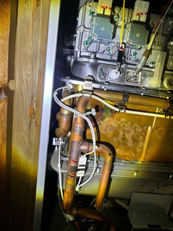 Completed preventive plumbing maintenance inspection on tankless water heater system. Inspected exterior venting components including PVC exhaust termination and intake piping mounted on building exterior wall. Verified proper clearances and secure mounting of vent pipes and covers. Examined internal heating components, burner assembly, and heat exchanger for signs of scaling or corrosion. Inspected gas valve connections, ignition system wiring, and control board functionality. Verified proper operation of copper supply lines and condensate drainage system. All components found operating within normal parameters. Unit flushed and descaled per manufacturer specifications to maintain efficiency and prevent mineral buildup in heat exchanger. System tested and confirmed proper ignition sequence and temperature output.