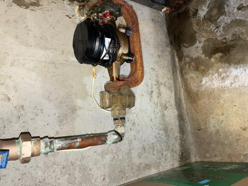 Responded to reported water leak from shut-off valve in basement. Upon inspection, identified active leak at corroded shut-off valve assembly connected to water meter. The existing valve exhibited severe corrosion and oxidation on copper piping and brass fittings, with visible rust patina and mineral deposits indicating prolonged moisture exposure. Shut off main water supply and replaced failed shut-off valve with new brass ball valve. Removed deteriorated section of copper pipe showing advanced corrosion and greenish oxidation buildup. Installed new copper pipe section using proper soldering techniques and secured all connections with appropriate brass compression fittings. Tested system for leaks by restoring water pressure and verified proper valve operation. Confirmed no active leaks at valve assembly or connections. Documented pre-existing conditions showing significant corrosion throughout plumbing assembly and water staining on concrete surfaces.