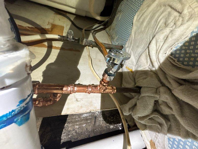 # Plumbing Service Report

During a kitchen sink installation, severely corroded water supply lines were discovered beneath the sink requiring immediate replacement. The existing copper piping showed significant deterioration at multiple connection points, posing a risk for future leaks and water damage.

Removed the compromised copper supply lines and associated fittings from the under-sink area. Installed new copper pipe assembly with properly soldered joints and chrome-plated shut-off valves to ensure reliable water flow control. All connections were tested for leaks and proper operation. The replacement piping was routed through the wall cavity with appropriate insulation to prevent condensation and protect against temperature fluctuations. Work area was cleared of debris and all plumbing fixtures were left in proper working condition, ready for completion of the kitchen sink installation.