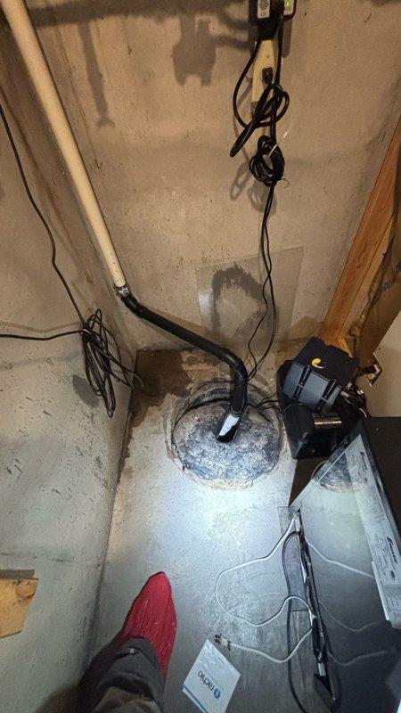# Basement Water Leak Repair

Responded to active water leak in basement of 25-year-old residential property. Upon arrival, conducted thorough inspection of affected area and identified water accumulation on concrete floor with visible staining and dampness around floor drain and sump pit area.

Assessed plumbing system components including drainage infrastructure and sump pump operation. Examined PVC piping along wall perimeter and verified proper connections. Inspected sump pump unit and associated discharge hose for proper function and potential failure points causing water intrusion.

Identified source of water leak and performed necessary repairs to restore proper drainage function. Verified all plumbing connections were secure and operating within normal parameters. Tested sump pump operation to ensure adequate water removal capacity and proper discharge through exterior drainage system.

Documented existing conditions including water damage patterns on concrete floor, condition 