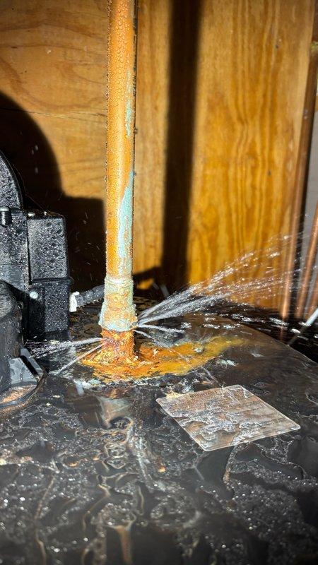 Responded to reported water leak from tanked water heater located in basement. Upon arrival, contacted customer via provided phone number with 30-minute notice as requested. Conducted diagnostic inspection of the water heater and associated plumbing components. Identified active leak originating from connection point at base of unit, evidenced by significant rust-colored staining, mineral deposits, and water damage on drip pan and surrounding area. Documented leak source and corrosion patterns with photographic evidence showing deteriorated connection point with ongoing moisture accumulation. Assessed circulation pump system and associated copper refrigerant lines with foam insulation in mechanical space. Noted compromised seal at pipe penetration point contributing to water intrusion and oxidation. Presented findings to customer and provided repair recommendations to address leak source and prevent further water damage to basement area.