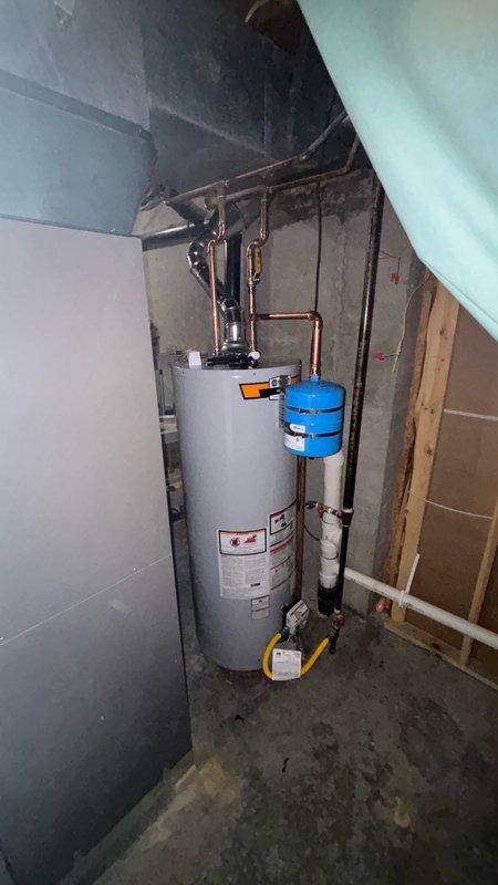 Completed installation of a 50-gallon gas-fired water heater in residential utility room. Unit was properly positioned and secured against concrete block wall with all necessary plumbing connections made using copper piping. Installed thermal expansion tank on the water supply line to protect against pressure buildup from thermal expansion. All gas connections, water supply lines, and temperature-pressure relief valve discharge piping were installed per manufacturer specifications and local code requirements. System was tested for proper operation and verified for no leaks. HVAC contractor to handle final collection of old equipment.