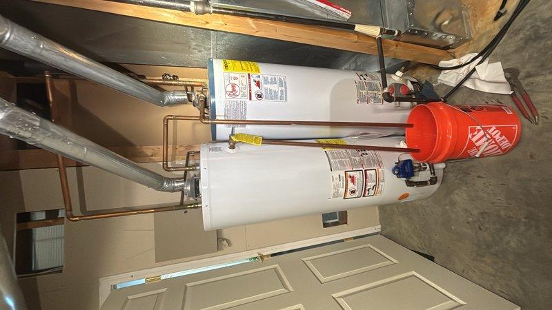 Completed installation of a 40-gallon gas water heater with thermal expansion tank in residential utility space. Removed existing unit and installed new water heater with proper venting, gas line connections, and copper supply piping with shutoff valves. Mounted red thermal expansion tank to accommodate thermal expansion in closed plumbing system per code requirements. All connections pressure tested and verified for proper operation and safety compliance.