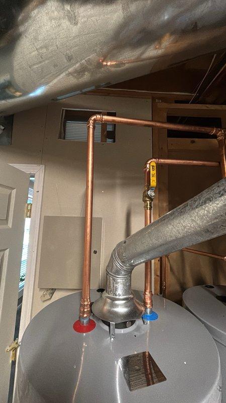 Completed installation of a 40-gallon gas water heater with thermal expansion tank in residential utility space. Removed existing unit and installed new water heater with proper venting, gas line connections, and copper supply piping with shutoff valves. Mounted red thermal expansion tank to accommodate thermal expansion in closed plumbing system per code requirements. All connections pressure tested and verified for proper operation and safety compliance.