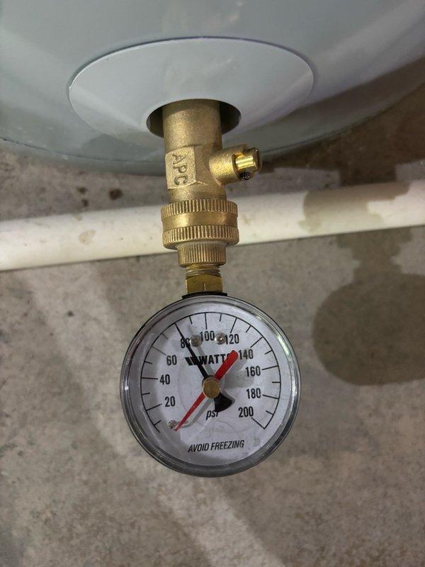 Completed plumbing maintenance inspection of residential HVAC air handler unit and water heater system. Inspected copper water supply lines with red and blue valve handles, verified proper brass fitting connections, and examined condensate reservoir assembly on air handler unit located in attic space. Evaluated water heater pressure relief valve assembly with WATTS pressure gauge reading 0-200 PSI range, confirmed proper mounting and fitting integrity at tank penetration point.
