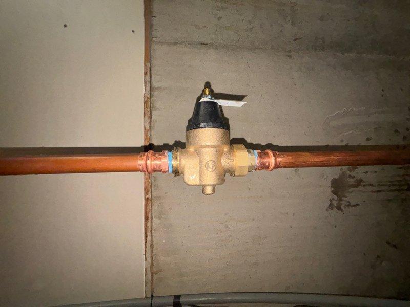 Responded to service call for faulty pressure regulator and shut-off valve on main water line. Successfully removed and replaced worn brass pressure reducing valve assembly with new unit, including compression fittings on copper supply piping. Additionally replaced deteriorated shut-off valve showing signs of oxidation and compromised operation. Both valves were installed along the main water supply line in the basement utility area, restoring proper water pressure regulation and shut-off capability to the system.