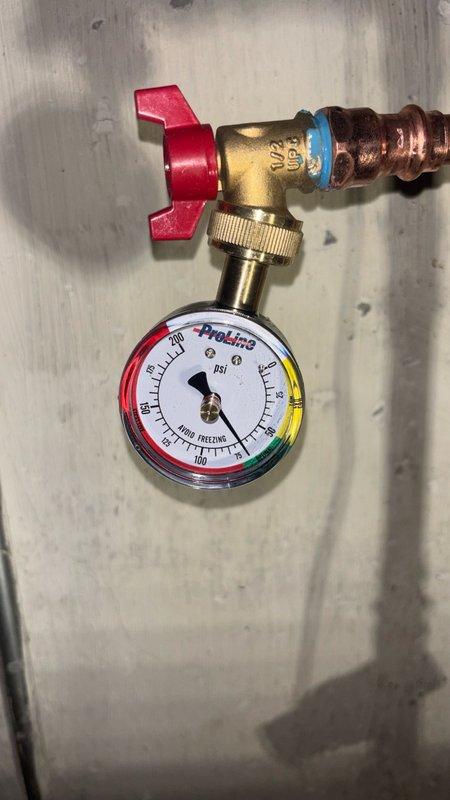 Responded to service call for low water pressure issue at residential property. Upon inspection, identified aging water meter and associated plumbing components as potential contributing factors to pressure concerns. Installed ProLine pressure gauge assembly with brass fittings and manual shutoff valve to monitor system pressure and facilitate diagnostics. Gauge installation included copper pipe connections and proper valve placement for accurate pressure readings. Documented existing conditions including water heater overflow valve actively leaking and requiring replacement. Photographed current plumbing configuration showing vertical copper supply line, existing meter assembly with visible wear and patina, and newly installed pressure monitoring equipment. Assessed water meter condition and determined replacement quotation needed due to age and deterioration of components. Provided customer with comprehensive evaluation of plumbing system status and recommended repair options for pre
