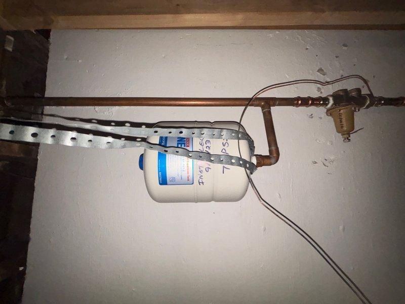 Responded to service call for tanked water heater not heating or turning on. Upon inspection, discovered significant water damage on utility room wall indicating previous or ongoing leak from water heater system. Examined water heater connections, copper supply lines, brass fittings, and associated plumbing components including whole-house water filtration system mounted in crawlspace area. Documented existing conditions with photographs showing extent of moisture damage, discoloration, and deterioration of wall surfaces near mechanical equipment. Assessed water heater functionality and related piping infrastructure to determine source of heating failure and water intrusion.