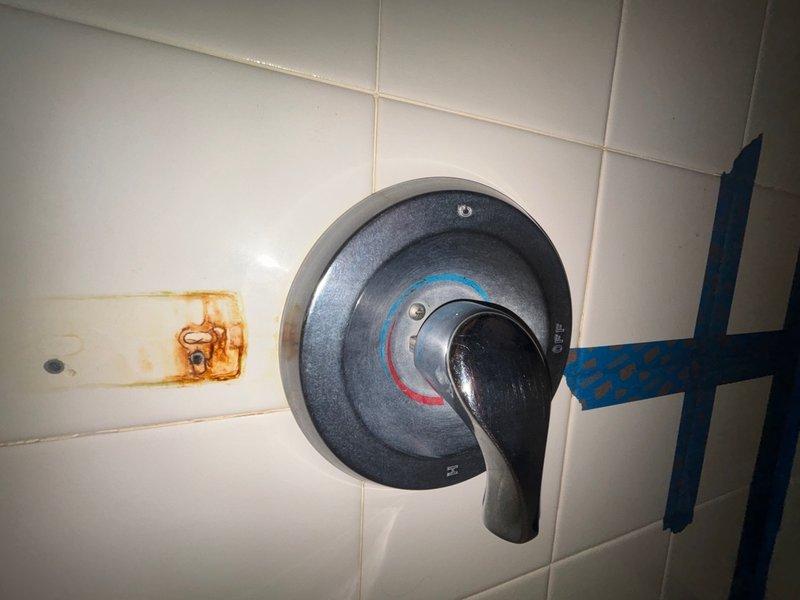 Completed comprehensive plumbing inspection of residential property. Identified two toilets with continuously running water caused by faulty fill valves and deteriorated flapper assemblies, evidenced by mineral buildup and rust staining in tank components. Documented shower valve assembly and noted significant water damage with mineral deposits on recessed soap dish, indicating potential grout seal failure requiring future attention.