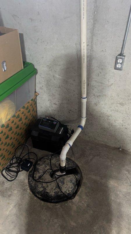 Replaced existing sump pump with new 1/3 HP unit installed in sump basin with grated cover. Routed two separate PVC drain lines across basement floor to sump pit to accommodate humidifier and air conditioning condensate drainage, ensuring proper gravity flow and connection to pump discharge system.