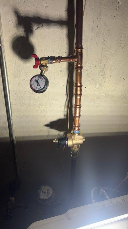Responded to callback regarding pipe vibration and singing noise following recent pressure reducing valve installation. Upon inspection, confirmed water pressure was within acceptable range as indicated by system gauge. Identified water hammer condition caused by PRV setting creating excessive flow velocity through copper piping. Adjusted PRV to optimize pressure balance, reducing vibration while maintaining adequate system pressure. Verified all soldered joints and connections at water heater assembly for security. Tested system operation and confirmed elimination of singing noise in pipes throughout pressure cycles.