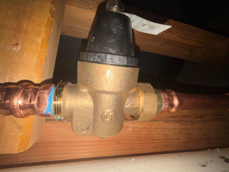Installed a 3/4" brass pressure reducing valve (PRV) on the main water line in the attic space, connecting it between existing copper piping using compression fittings to regulate incoming water pressure. Repaired a woodford-style frost-proof hose bib by installing new copper piping with proper expansion loop configuration and securing all connections with soldered joints and appropriate mounting hardware to wooden framing members.