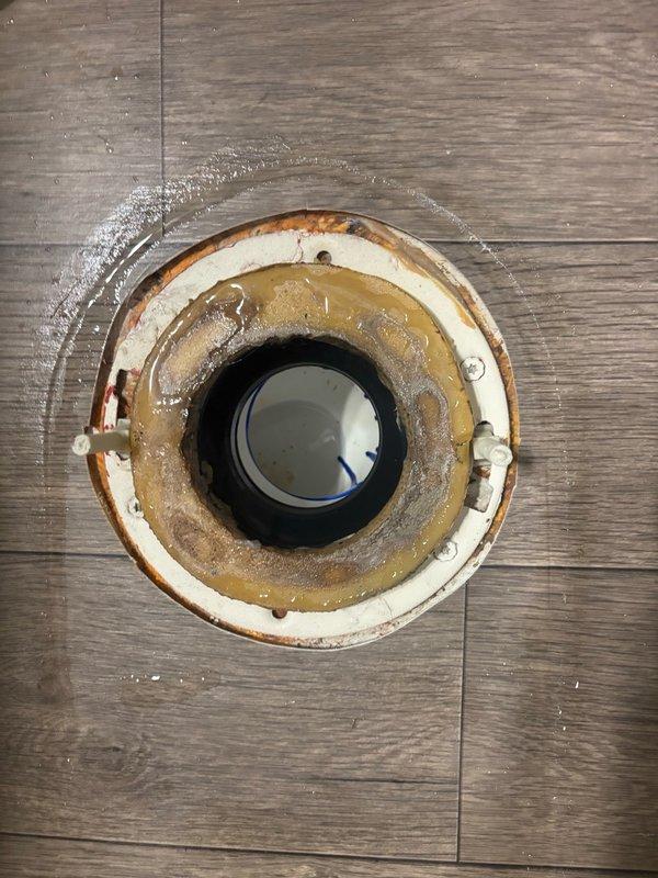 Responded to reported kitchen sink backup causing flooding in multiple areas of the home. Upon investigation, discovered the issue extended beyond the kitchen sink to involve compromised drainage system components. Accessed wall cavity to inspect vertical drain stack and found deteriorated toilet flange with significant rust staining and moisture damage indicating long-term water exposure. The wax ring showed advanced age and deterioration, contributing to improper sealing and water escape. Removed damaged flange components and prepared substrate for replacement installation. Inspected vertical PVC drain pipe within wall cavity to ensure proper drainage flow and verified no additional blockages or structural concerns with the drain stack. Documented existing conditions including exposed framing, insulation, and drainage components. Addressed immediate drainage concerns and prepared system for necessary repairs to restore proper function and prevent further water damage to surrounding a