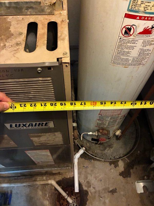 Responded to report of leaking gas-fired tanked water heater located in office closet. Upon arrival, performed visual inspection of the unit and surrounding utility area, documenting existing conditions including proximity to HVAC equipment and plumbing connections. Assessed water heater tank condition, shut-off valves with red handles, and copper and PVC pipe connections at base of unit. Identified evidence of moisture damage on concrete surfaces and walls in utility space, with visible staining and discoloration indicating ongoing or previous water intrusion. Evaluated clearance requirements between water heater and adjacent Luxaire furnace unit. Photographed installation setup, piping configuration, safety labels, and areas of concern for documentation purposes.