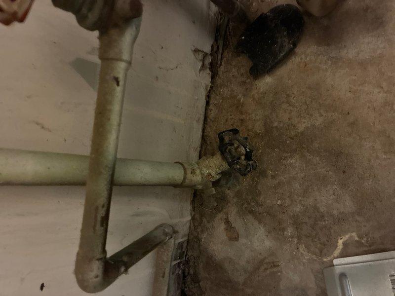 Responded to report of leaking gas-fired tanked water heater located in office closet. Upon arrival, performed visual inspection of the unit and surrounding utility area, documenting existing conditions including proximity to HVAC equipment and plumbing connections. Assessed water heater tank condition, shut-off valves with red handles, and copper and PVC pipe connections at base of unit. Identified evidence of moisture damage on concrete surfaces and walls in utility space, with visible staining and discoloration indicating ongoing or previous water intrusion. Evaluated clearance requirements between water heater and adjacent Luxaire furnace unit. Photographed installation setup, piping configuration, safety labels, and areas of concern for documentation purposes.