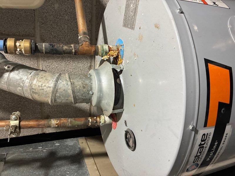 Completed routine plumbing maintenance inspection of residential water heater and shower fixtures. Documented significant corrosion and mineral buildup on water heater pipe connections and fittings, particularly around brass connections with blue valve assembly. Verified shower installation with chrome fixtures and handheld shower assembly functioning properly.